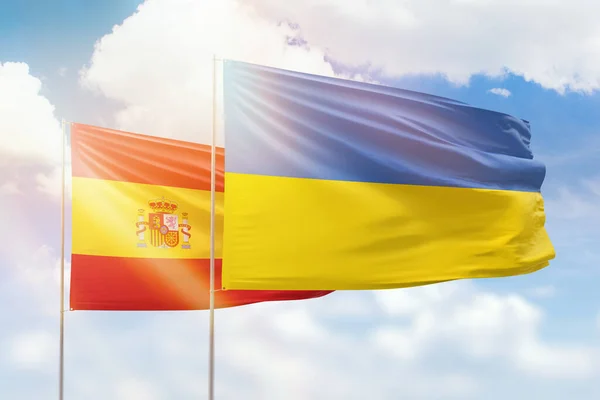 Sunny blue sky and flags of ukraine and spain