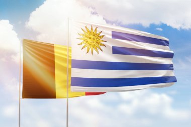 Sunny blue sky and flags of uruguay and belgium