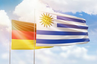 Sunny blue sky and flags of uruguay and germany