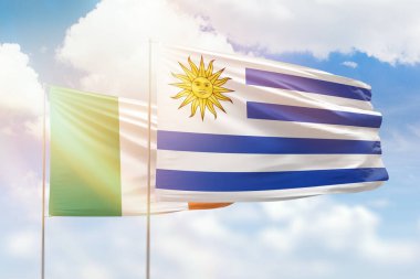 Sunny blue sky and flags of uruguay and ireland