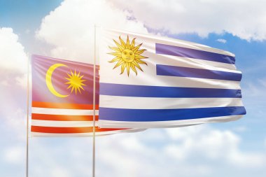 Sunny blue sky and flags of uruguay and malaysia