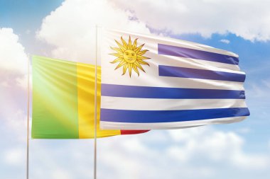 Sunny blue sky and flags of uruguay and mali