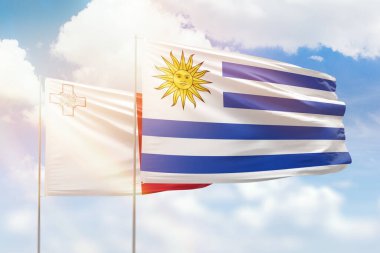 Sunny blue sky and flags of uruguay and malta