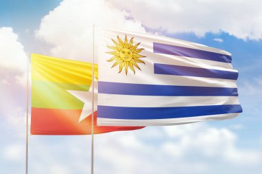 Sunny blue sky and flags of uruguay and myanmar