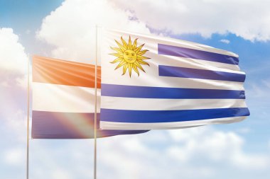 Sunny blue sky and flags of uruguay and netherlands