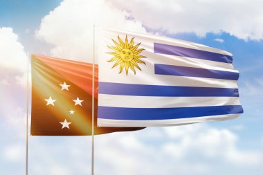 Sunny blue sky and flags of uruguay and papua new guinea