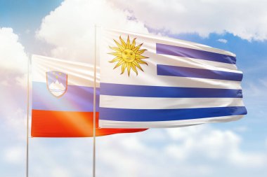 Sunny blue sky and flags of uruguay and slovenia