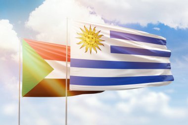 Sunny blue sky and flags of uruguay and sudan