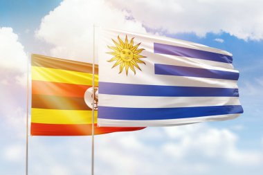 Sunny blue sky and flags of uruguay and uganda