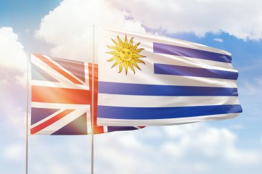 Sunny blue sky and flags of uruguay and united kingdom