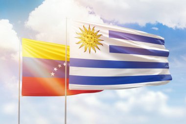 Sunny blue sky and flags of uruguay and venezuela