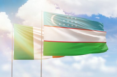Sunny blue sky and flags of uzbekistan and ireland