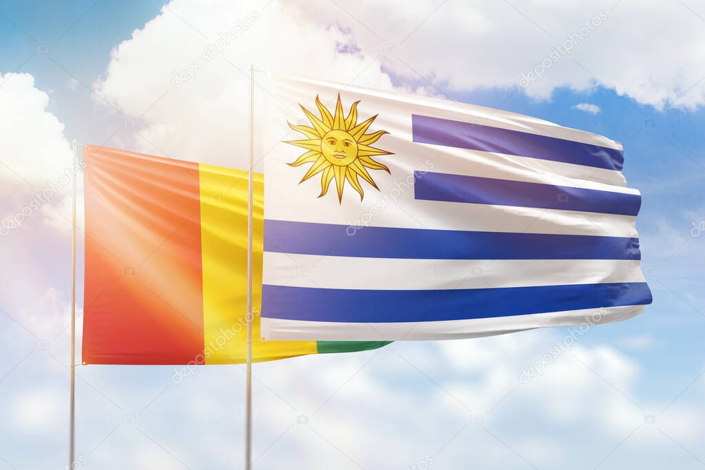 Sunny blue sky and flags of uruguay and guinea
