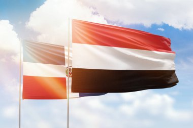 Sunny blue sky and flags of yemen and dominican republic