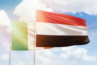 Sunny blue sky and flags of yemen and ireland