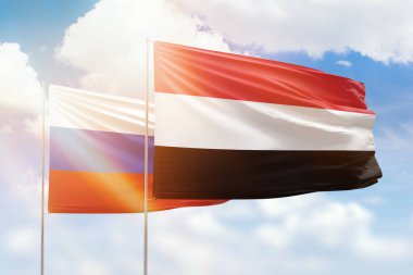 Sunny blue sky and flags of yemen and russia