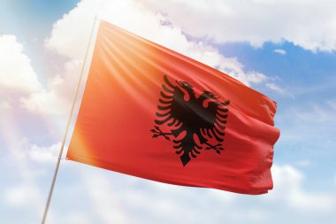 Sunny blue sky and a flagpole with the flag of albania