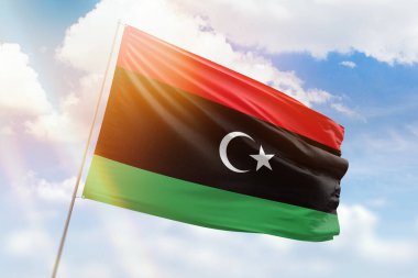 Sunny blue sky and a flagpole with the flag of libya