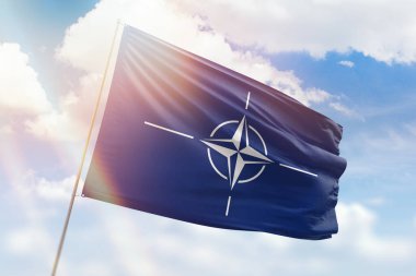 Güneşli mavi gökyüzü ve NATO bayrağıyla bayrak direği