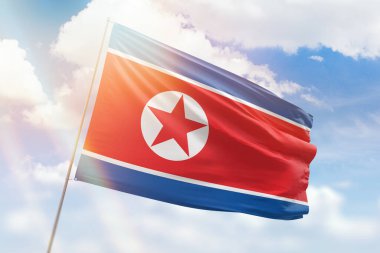 Güneşli mavi gökyüzü ve Kuzey Kore bayrağıyla bayrak direği