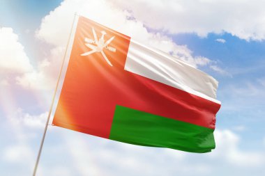 Sunny blue sky and a flagpole with the flag of oman