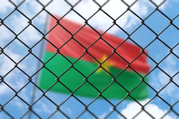 A steel mesh against the background of a blue sky and a flagpole with the flag of burkina faso