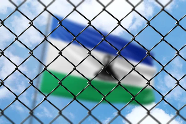 A steel mesh against the background of a blue sky and a flagpole with the flag of lesotho