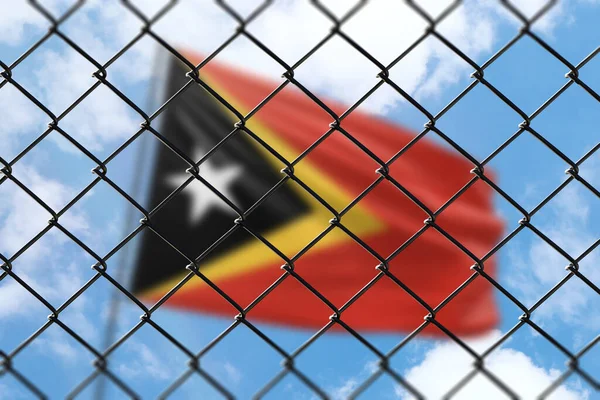 A steel mesh against the background of a blue sky and a flagpole with the flag of timor leste