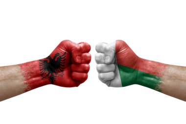 Two hands punch to each others on white background. Country flags painted fists, conflict crisis concept between albania and madagascar