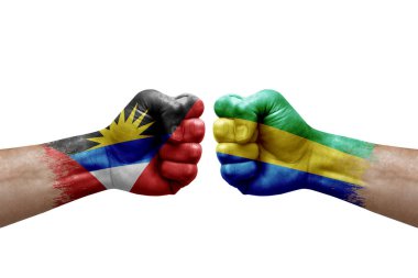 Two hands punch to each others on white background. Country flags painted fists, conflict crisis concept between antigua and barbuda and gabon