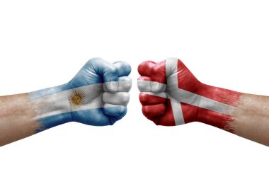 Two hands punch to each others on white background. Country flags painted fists, conflict crisis concept between argentina and denmark