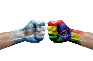 Two hands punch to each others on white background. Country flags painted fists, conflict crisis concept between argentina and ethiopia