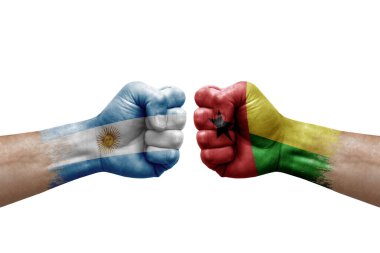 Two hands punch to each others on white background. Country flags painted fists, conflict crisis concept between argentina and guinea-bissau