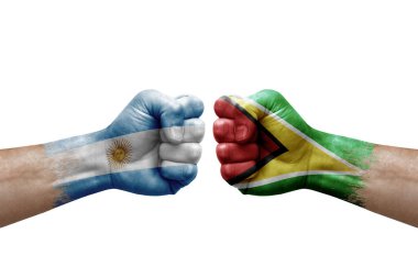 Two hands punch to each others on white background. Country flags painted fists, conflict crisis concept between argentina and guyana