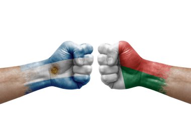 Two hands punch to each others on white background. Country flags painted fists, conflict crisis concept between argentina and madagascar