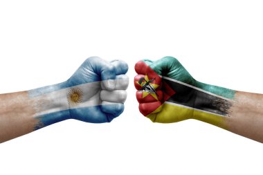 Two hands punch to each others on white background. Country flags painted fists, conflict crisis concept between argentina and mozambique