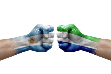 Two hands punch to each others on white background. Country flags painted fists, conflict crisis concept between argentina and sierra leone