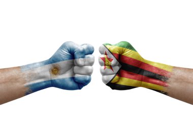 Two hands punch to each others on white background. Country flags painted fists, conflict crisis concept between argentina and zimbabwe