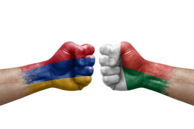 Two hands punch to each others on white background. Country flags painted fists, conflict crisis concept between armenia and madagascar