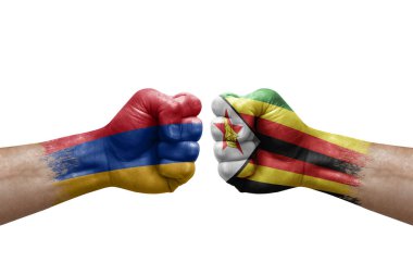 Two hands punch to each others on white background. Country flags painted fists, conflict crisis concept between armenia and zimbabwe