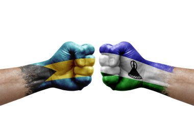 Two hands punch to each others on white background. Country flags painted fists, conflict crisis concept between bahamas and lesotho