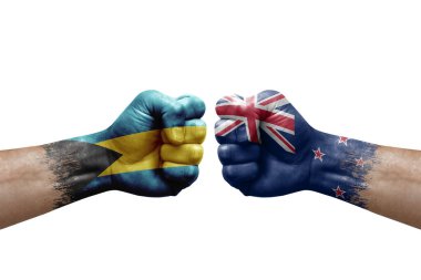 Two hands punch to each others on white background. Country flags painted fists, conflict crisis concept between bahamas and new zealand