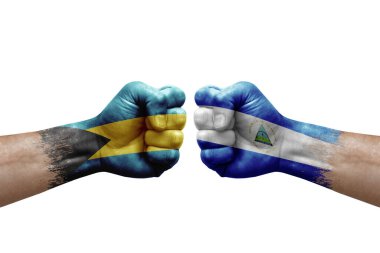 Two hands punch to each others on white background. Country flags painted fists, conflict crisis concept between bahamas and nicaragua