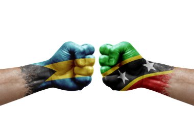 Two hands punch to each others on white background. Country flags painted fists, conflict crisis concept between bahamas and saint kitts and nevis