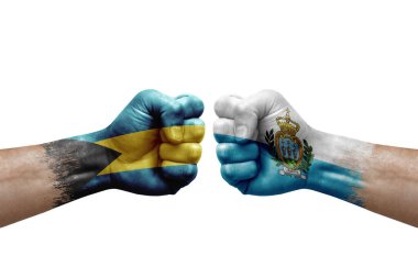Two hands punch to each others on white background. Country flags painted fists, conflict crisis concept between bahamas and san marino