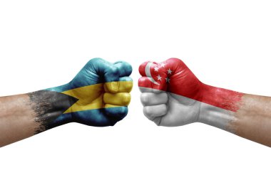 Two hands punch to each others on white background. Country flags painted fists, conflict crisis concept between bahamas and singapore