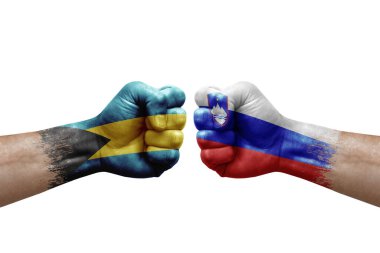 Two hands punch to each others on white background. Country flags painted fists, conflict crisis concept between bahamas and slovenia