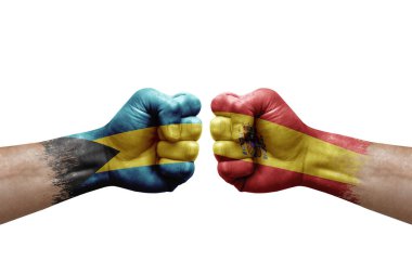 Two hands punch to each others on white background. Country flags painted fists, conflict crisis concept between bahamas and spain