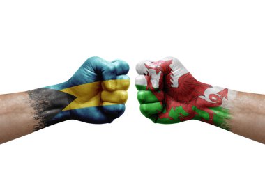 Two hands punch to each others on white background. Country flags painted fists, conflict crisis concept between bahamas and wales