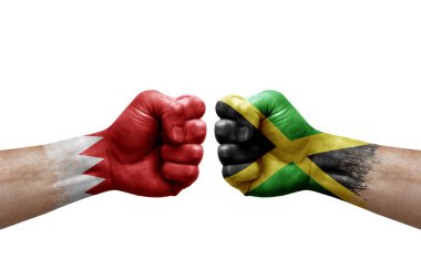 Two hands punch to each others on white background. Country flags painted fists, conflict crisis concept between bahrain and jamaica